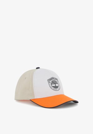 Casquette de baseball bicolore avec des panneaux beige et blanc, une visière orange vif, et le logo Timberland sur le panneau avant.