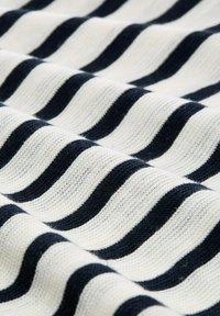 Golfgestreepte stof in crème en marineblauw met een zachte textuur. Toont afwisselend brede en smalle strepen.