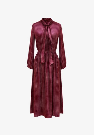 Bordowa sukienka w kropki z długimi rękawami, kołnierzykiem w kształcie kokardy i dopasowaną talią, wykonana z gładkiego, błyszczącego materiału.