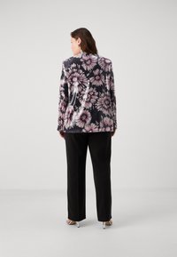 Blommig kavaj i svart med rosa och vita blommönster, tillsammans med svarta byxor och silvriga högklackade sandaler. Slät textur.