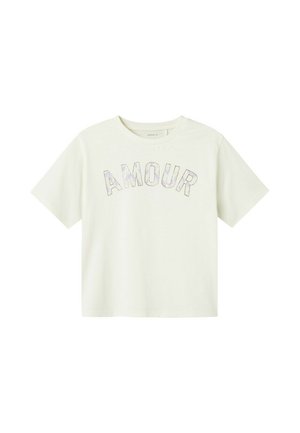 T-shirt en crème à manches courtes avec le mot "AMOUR" en lettres iridescentes. Matière en coton douce avec une coupe décontractée. Encolure ras du cou.
