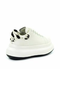 Białe sneakersy na platformie z czarno-białym, nakrapianym detalem na pięcie oraz grubą białą podeszwą z czarnym spodem.