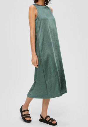 Ærmeløs kjole til knæet i en afdæmpet grøn farve, lavet af glat stof med en afslappet pasform. Kombineret med sorte sandaler med stropper.