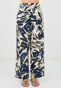 Pantalons larges en tissu léger arborant un motif abstrait dans des tons marine, beige et crème. Taille élastique pour plus de confort.