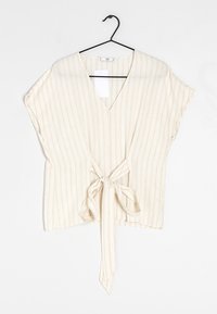 Beżowa bluzka w paski z głębokim dekoltem w serek, krótkimi rękawami i wiązaniem w talii. Wykonana z lekkiego materiału o miękkiej fakturze.
