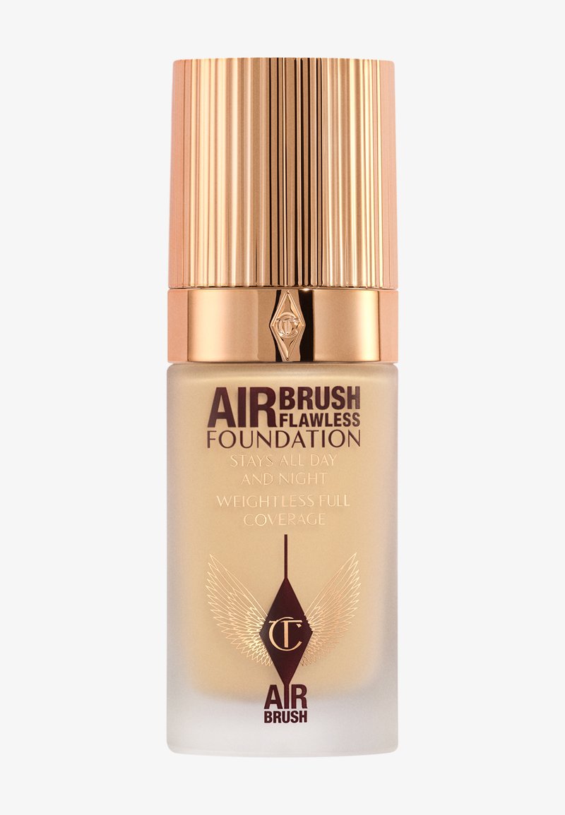 Charlotte Tilbury Airbrush Flawless Foundation bottle with gold ribbed cap, beige liquid foundation, and winged logo on frosted glass.