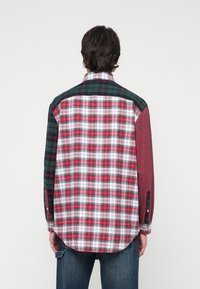 Karierte Hemd mit einer Mischung aus roten, grünen und weißen Mustern, mit kontrastierenden Stoffpaneelen und Knopfmanschetten. Lange Ärmel, abgerundeter Saum.