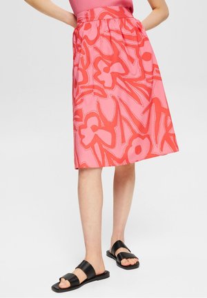 Jupe midi rose avec un motif floral rouge. Présente une taille élastique froncée et est fabriquée en tissu léger.