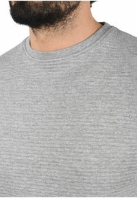 Gray crew neck shirt featuring a textured fabric with subtle horizontal stripes, smooth texture, and a relaxed fit.
