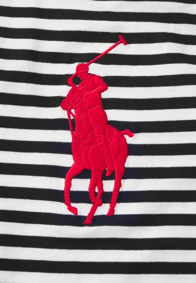 Κόκκινος κεντημένος παίκτης πόλο πάνω σε άλογο που κρατάει μαλέτα, σε φόντο με υφάσματα μαύρου και λευκού οριζόντιου ριγέ.