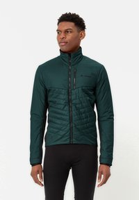 Giacca da uomo con zip di colore verde scuro, caratterizzata da una texture trapuntata nel torso, maniche lisce e un colletto alto. Dettagli neri lungo i fianchi.