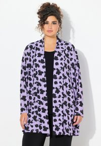 Violetti neuletakki, jossa on musta kukkakuosi, pitkät hihat ja avoin etuosa. Puettu mustan paidan päälle. Pehmeä kangas.