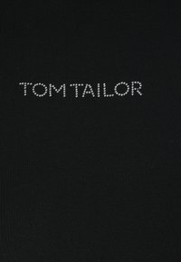Black fabric top featuring “TOM TAILOR” logo in shiny silver studs, arranged in a clean, uppercase font on a smooth textured surface.