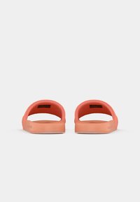 Koraljørne fargede sandaler med åpen design, glatt tekstur og formet såle. Har en avrundet form og minimalistiske merkevaredetaljer.