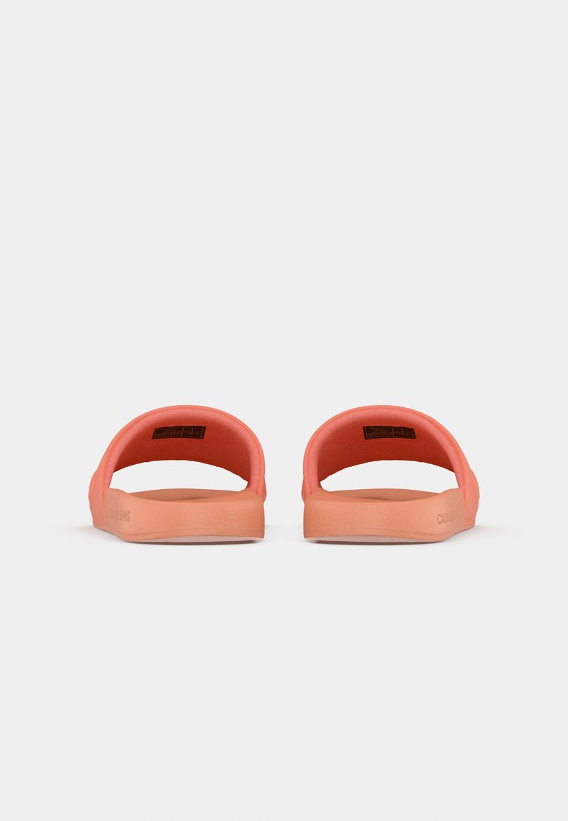 Sandalias de slide color coral con diseño abierto, textura suave y suela contorneada. Presentan una forma redondeada y detalles de marca minimalistas.