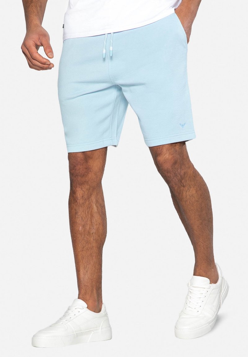 Shorts bleu clair, arrivant au genou, fabriqués en tissu doux avec une taille élastique et un cordon de serrage. Détail de logo subtil à l’avant.