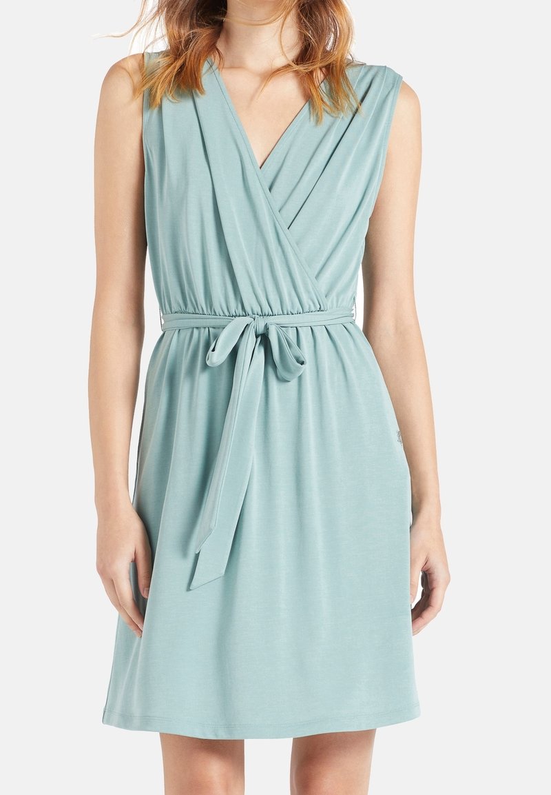 Robe portefeuille en teal clair fabriquée en tissu doux. Conception sans manches avec une taille ceinturée et un ourlet droit, présentant une texture lisse et un minimalisme dans les détails.