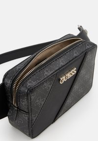 Schwarze Umhängetasche mit geprägt Monogramm-Muster. Verfügt über einen Reißverschluss in Goldoptik und ein Markenlogo auf der Vorderseite. Glatte Textur, rechteckige Form.