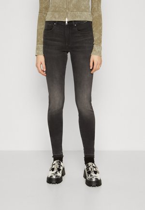 Sorte skinny jeans med en vaskefinish, med midjehøyde og fem-lomme-design, paret med metalliske sølvplattformer.