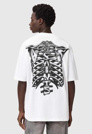Weißes, übergroßes T-Shirt mit einem großen schwarzen Skelett-Rippenkorb-Design auf der Rückseite, mit kurzen Ärmeln und einem lässigen Schnitt.