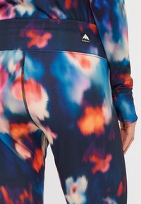 Hulahopke visoke pasnice z barvito abstraktno vzorcem v modrih, roza in oranžnih tonih. Opremljene z črnim logotipom blagovne znamke na pasu.