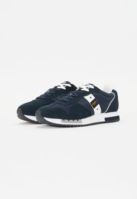 Zapatillas azul marino que combinan materiales de ante y malla, con acentos blancos, cierre con cordones y suela de goma con textura.
