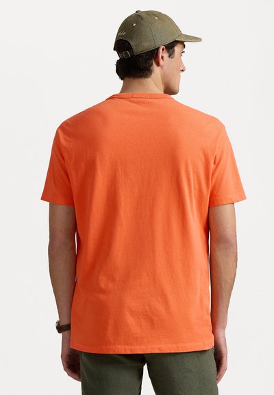 Kortärmad t-shirt i klar orange bomull, med rund hals och avslappnad passform. Baksidan har en enkel design utan tryck.