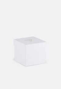 Valge kast tekstureeritud pinnaga, ruudukujuline, mille peal on väike kuldne kolmnurga logo. Minimalistlik disain ja lihtne sulgemine.