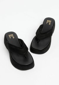 Paire de sandales tongs noires à plateforme avec larges brides en tissu et l'inscription « friends like these… » imprimée en doré sur les semelles intérieures.