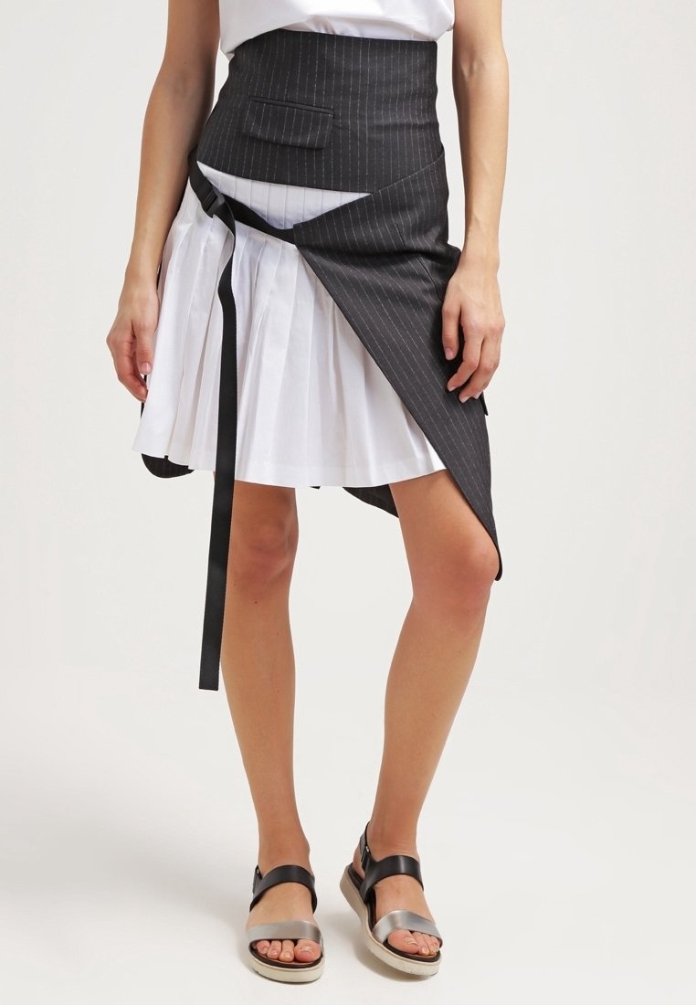 Svart randig kjol med vit veckad underkjol, med en midjeband och en ficka, kompletterad med svarta och silverfärgade sandaler.