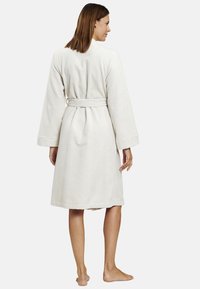 Cremefarbener, knielanger Bademantel aus samtigem Stoff mit langen Ärmeln, einem gebundenen Taillengürtel und einem schlichten, glatten Design.