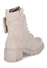 Stivaletto beige in similpelle con texture, con chiusura frontale a lacci, cerniera laterale e suola chunky con scanalature. Presenta un piccolo tirante posteriore per facilità d'uso.