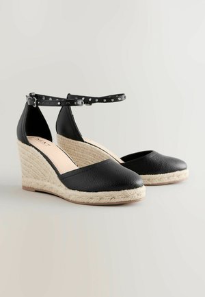 Mustad musta värvi espadrillid tekstuurse nahkatekkega, jute-kattega platvorm, pahkluu rihm hõbedaste nukkidega, ümar varvas.
