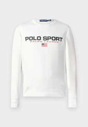 Sweatshirt à manches longues blanc avec le texte "POLO SPORT RALPH LAUREN" en noir et rouge, et un petit drapeau américain en dessous du texte.