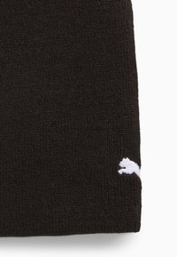 Bonnet noir en tricot avec une texture côtelée. Présente un logo blanc d'un félin bondissant sur le côté. Tissu robuste pour la chaleur et la durabilité.