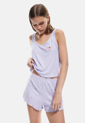 Débardeur violet clair à côtes avec un motif de chien et un short assorti qui présente un ourlet en dentelle et de petits motifs de chiens. Texture de tissu douce.