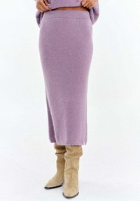 Lawendowa dzianinowa spódnica o prostym kroju, z prążkowanym paskiem i miękką fakturą. Zestawiona z beżowymi kozakami za kolano dla kontrastu.