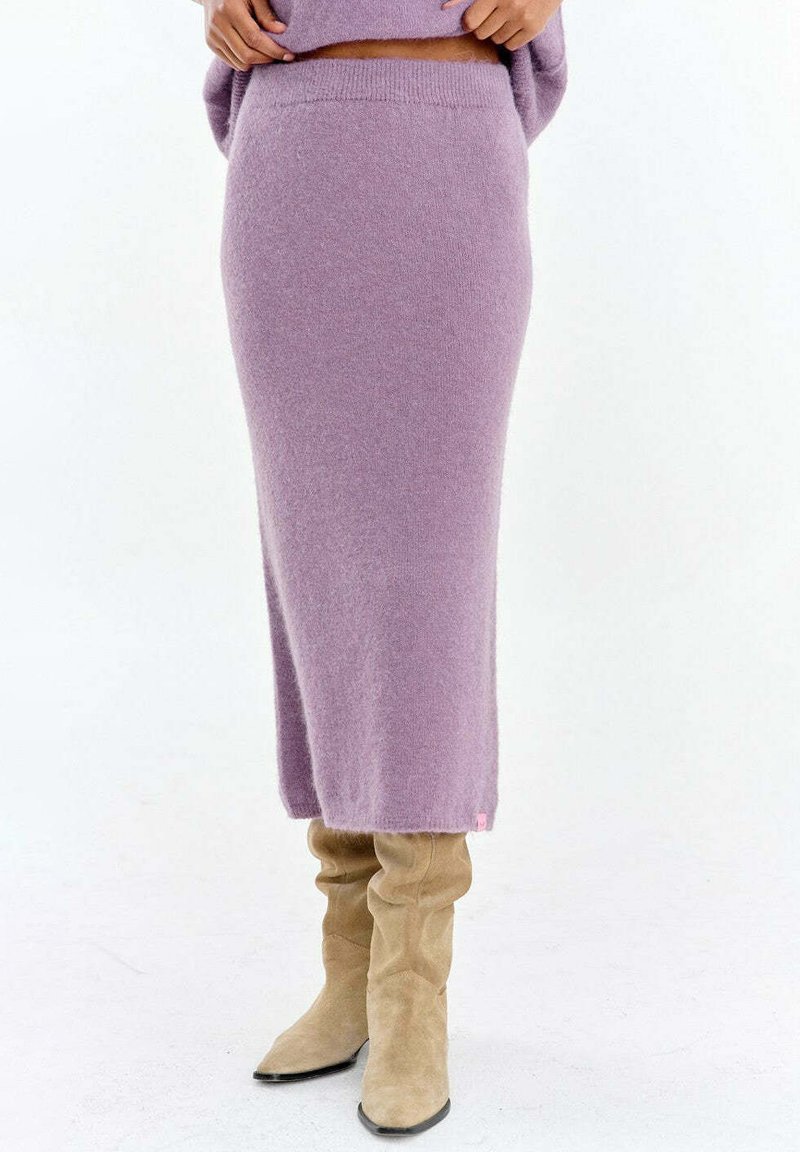 Lawendowa dzianinowa spódnica o prostym kroju, z prążkowanym paskiem i miękką fakturą. Zestawiona z beżowymi kozakami za kolano dla kontrastu.