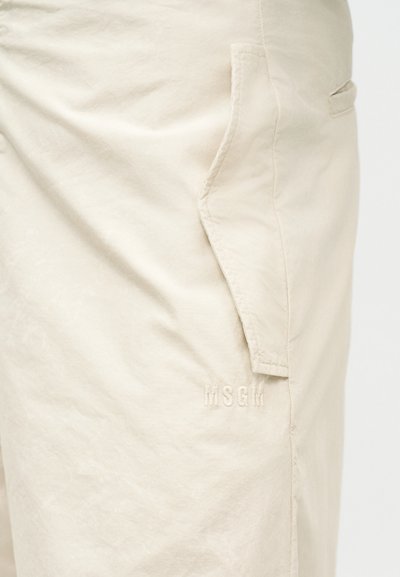 Shorts beige avec poche à rabat latérale et détail du logo MSGM brodé sur la cuisse.