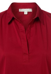 Rote Bluse mit Kragen und einer Detailknopfleiste, aus glattem Stoff mit leichtem Glanz, Etikett sichtbar mit Größe 36.