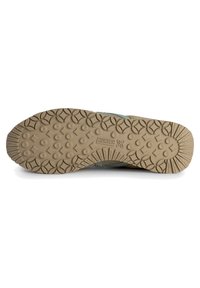 Suela de goma marrón texturizada con un patrón de agarre, que presenta formas circulares y de diamante. Parte superior de tela verde claro con acentos reforzados.
