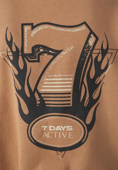 Ruskea kangas, jossa on rohkea musta ja kultainen grafiikka, jossa on numero 7, liekkejä ja teksti "7 DAYS ACTIVE" ympyrämuodostelmassa.