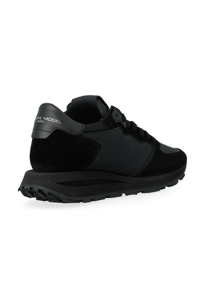 Sneaker nera con una combinazione di materiali in camoscio e mesh, colletto imbottito e suola in gomma testurizzata. Logo del marchio sul tallone.