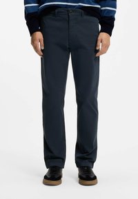 Marineblaue Chinos mit geradem Bein, Reißverschluss und Knopfverschluss. Verfügt über Seitentaschen und eine glatte Stoffstruktur.