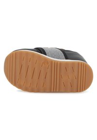 Black sneaker with gray and white striped textile detailing, rubber sole featuring grooves for grip, and a rounded toe design.