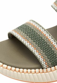 Green and beige slide sandal featuring woven straps with white and orange accents, soft footbed, and textured sole with raised edges.
