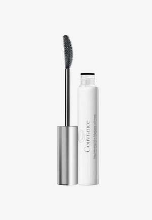 Curved mascara wand with black bristles beside a white tube labeled "Couvrance Hochverträgliche Mascara schwarz."