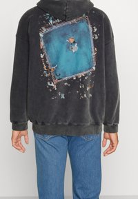 Zwarte hoodie met een grote blauwe grafiek op de achterkant die een ring en toeschouwers afbeeldt. Katoenmengsel met een zachte textuur.