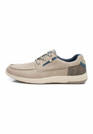 Zapatillas de deporte color beige claro con tejido texturizado, acentos azul oscuro, diseño con cordones y una suela acolchada; cuentan con costuras y detalles perforados.