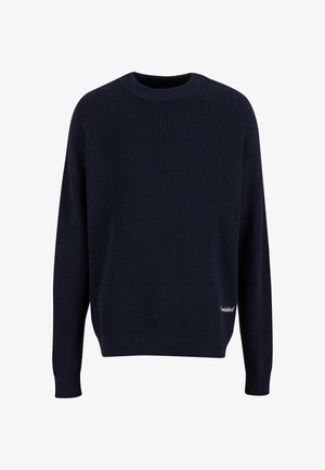 Marineblå ribbestrikket sweater med rund halsudskæring, sænkede skuldre og tætsiddende manchetter. Lille logoaccent på den nederste højre side.